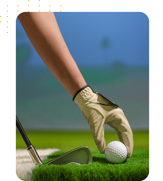 Golfer placing ball on tee with a gloved hand.